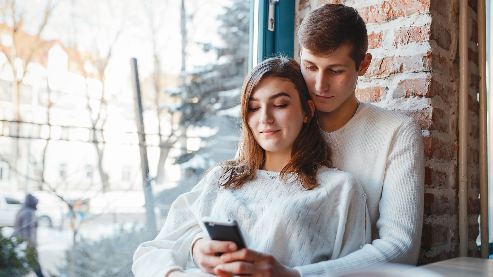 dvoje ljudi gledaju u telefon
